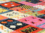 Nahaufnahme eines bunten Designer-Teppichs mit geometrischen Mustern in lebendigen Farben wie Rot, Pink, Gelb und Blau.