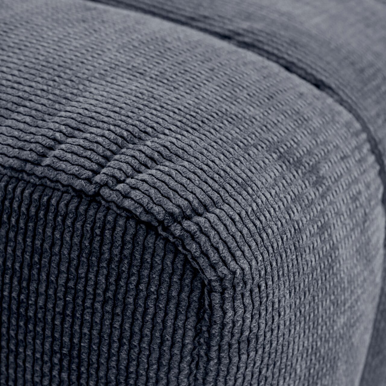 Nahaufnahme eines grauen, strukturierten Hockers aus Stoff, seitliche Perspektive