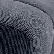 Nahaufnahme eines grauen, strukturierten Hockers aus Stoff, seitliche Perspektive