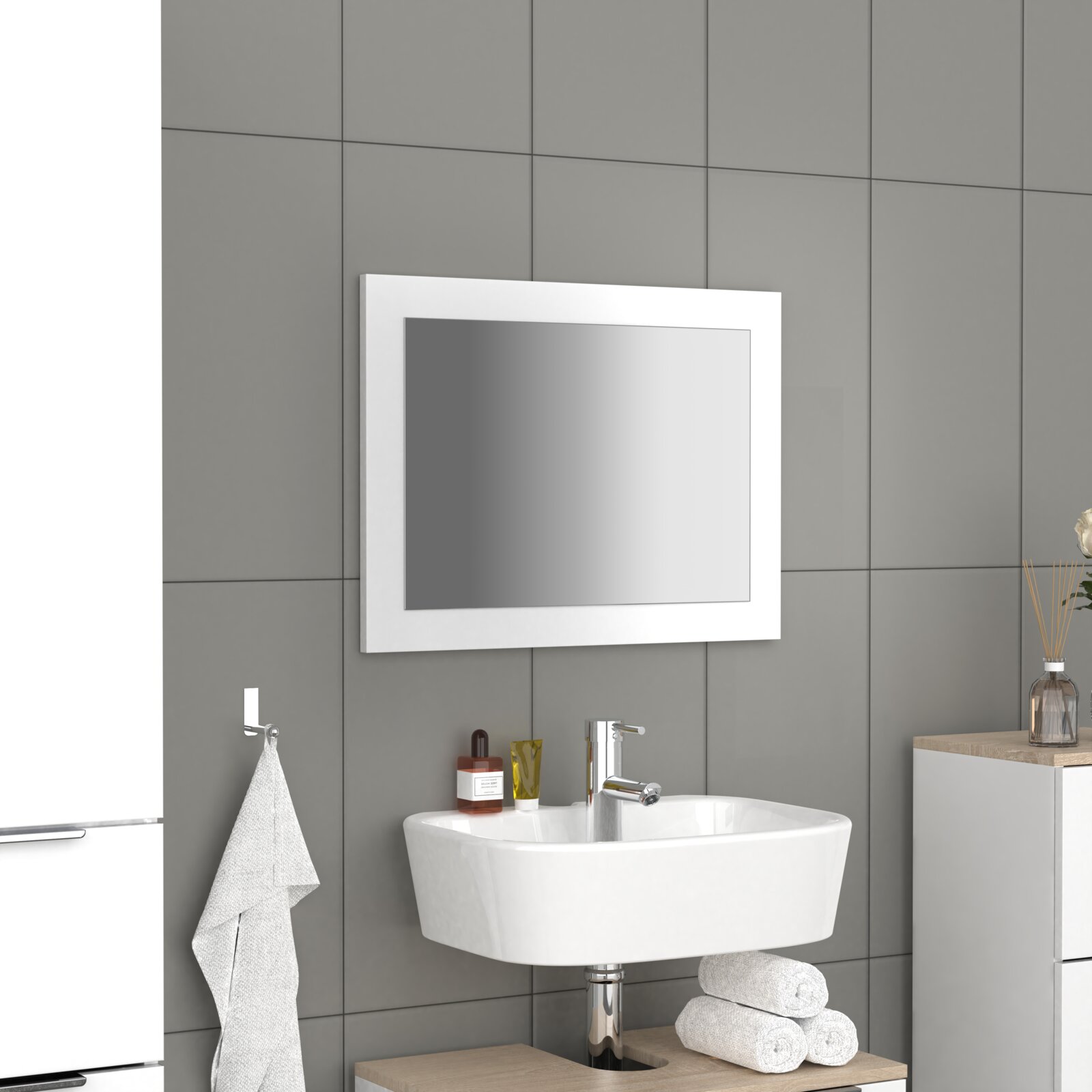 Rechteckiger Badspiegel mit weißem Rahmen über einem Waschbecken im modernen Badezimmer, leicht schräg von vorn aus Perspektive auf Augenhöhe fotografiert