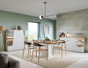 Moderner Esstisch in einem stilvollen Esszimmer mit grüner Wand, umgeben von eleganten Stühlen und Vitrinen, aus der Perspektive des Raumes betrachtet.