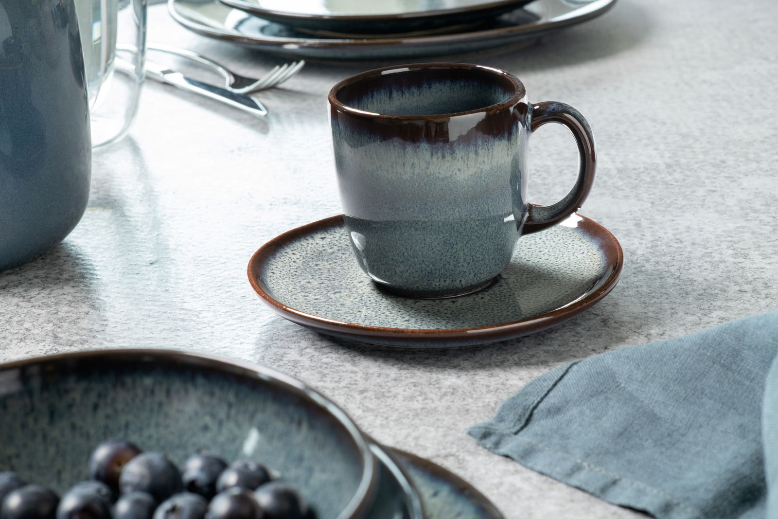 Like by Villeroy & Boch Untertasse LAVE GRIS Kaffeeuntertasse Lave grau mit passender Tasse, seitliche Perspektive auf einem gedeckten Tisch.