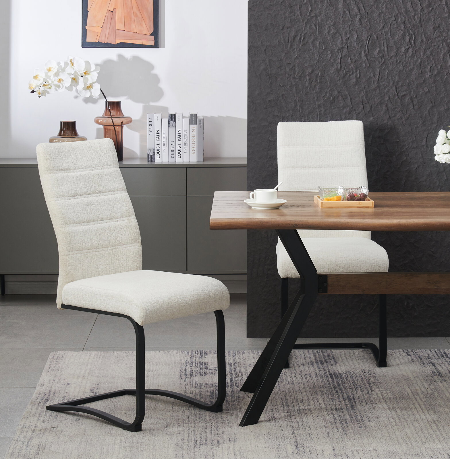 Beiger, gepolsterter Freischwinger-Esszimmerstuhl mit hoher Rückenlehne und schwarzem Metallgestell neben einem Holzesstisch im modernen Essbereich, Perspektive: seitliche Frontansicht auf Stuhl und Tisch.