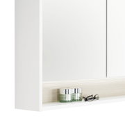 Nahaufnahme eines weißen Spiegelschranks mit zwei Glastiegeln und einer Brille auf einem Regalbrett.