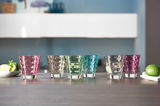 Sechsteiliges farbiges Becherset Leonardo OPTIC, frontal auf einem Tisch arrangiert, mit verschiedenen Farben und strukturiertem Design.