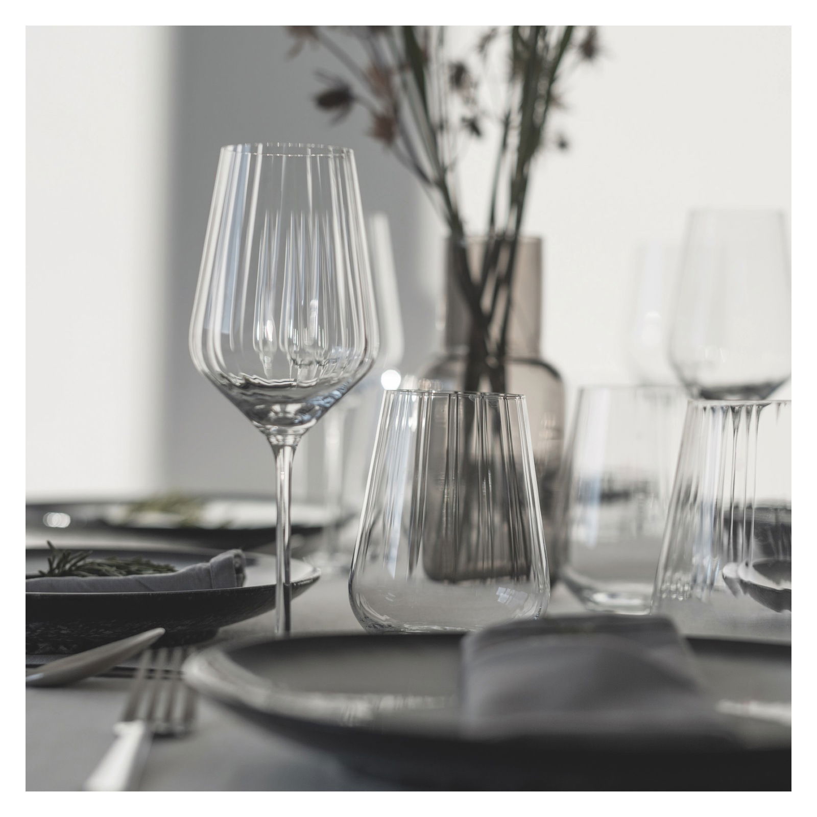 Elegantes Rotweinset mit Sternschliff, bestehend aus verschiedenen Gläsern auf einem gedeckten Tisch, seitliche Perspektive.