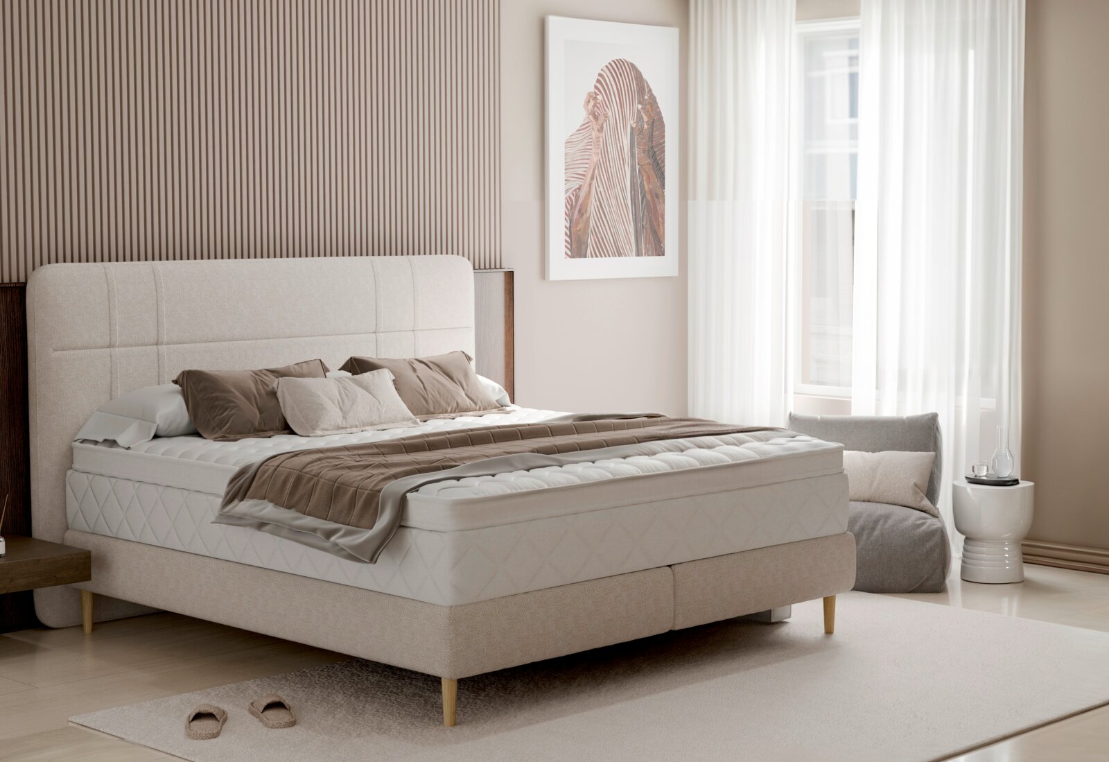 Beiges Boxspringbett mit gepolstertem Kopfteil, Matratze und brauner Tagesdecke in modernem Schlafzimmer, fotografiert aus leicht schräger Frontperspektive.