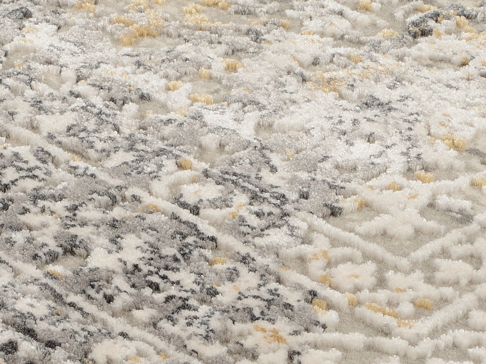 Nahaufnahme eines Designer-Teppichs mit weicher, flauschiger Textur in Grau- und Beigetönen, diagonale Perspektive.