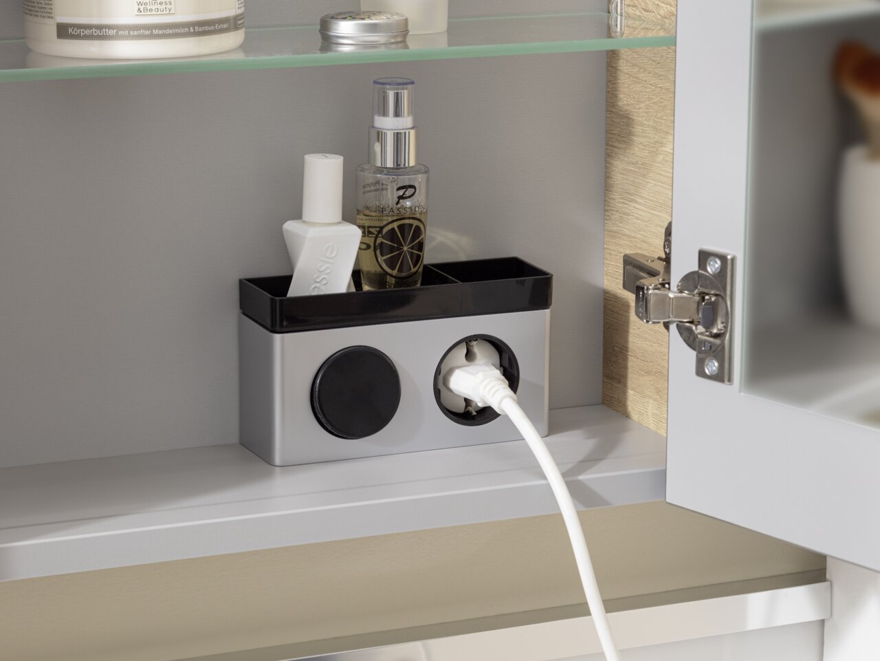 Voleo Spiegelschrank LARA Innenansicht eines Spiegelschranks mit Steckdose und Ablage für Kosmetikprodukte.
