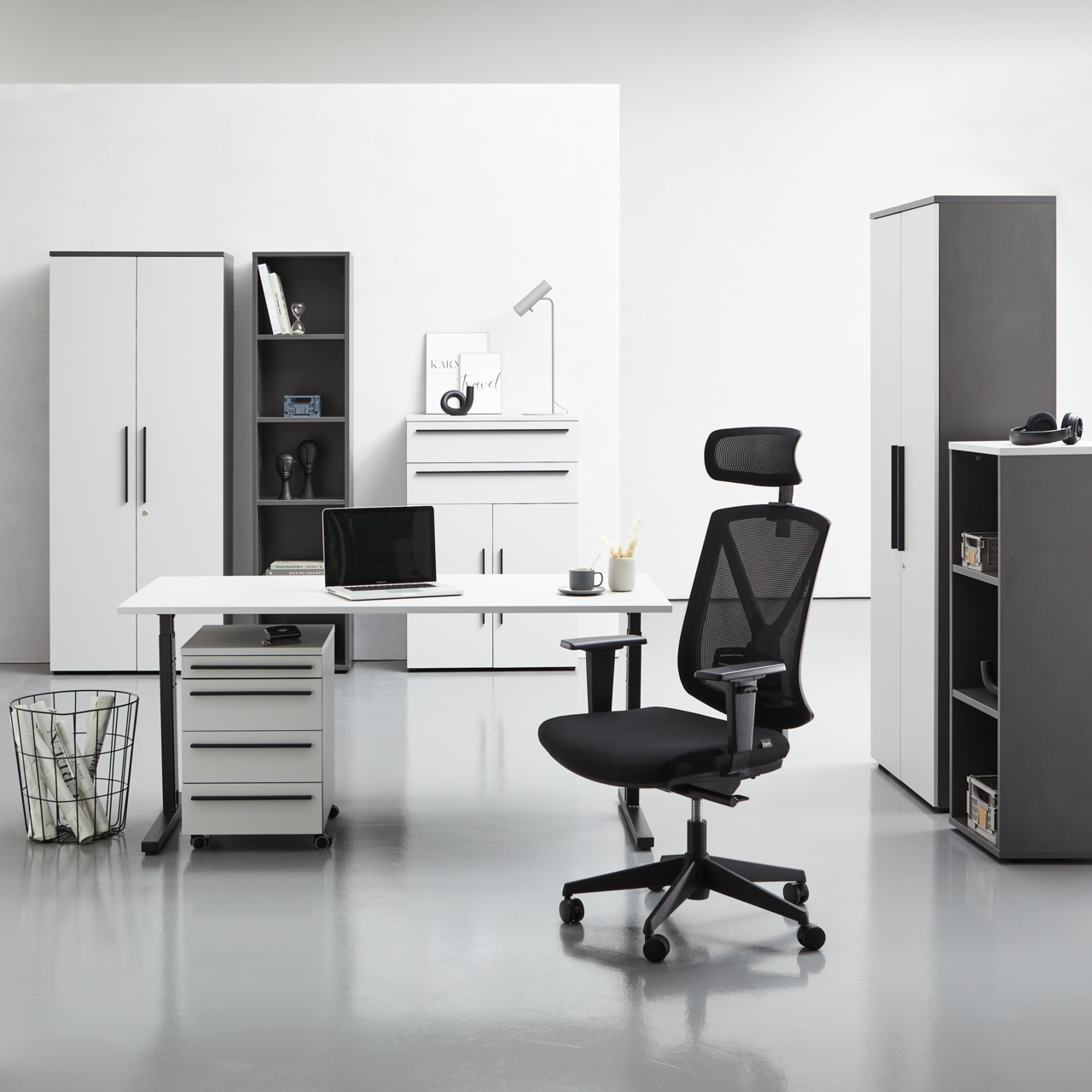 Novel Schreibtisch RENTON Moderne Büromöbel in einem hellen Raum, darunter ein Winkelschreibtisch, Rollcontainer, Aktenschränke und ein ergonomischer Bürostuhl. Frontalansicht.