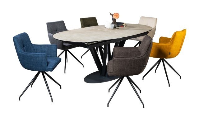 Moderne ovale eettafel met een lichtgekleurd tafelblad en een zwart metalen onderstel, omringd door zes gestoffeerde stoelen in verschillende kleuren; zijaanzicht in licht perspectief vanaf de voorkant.