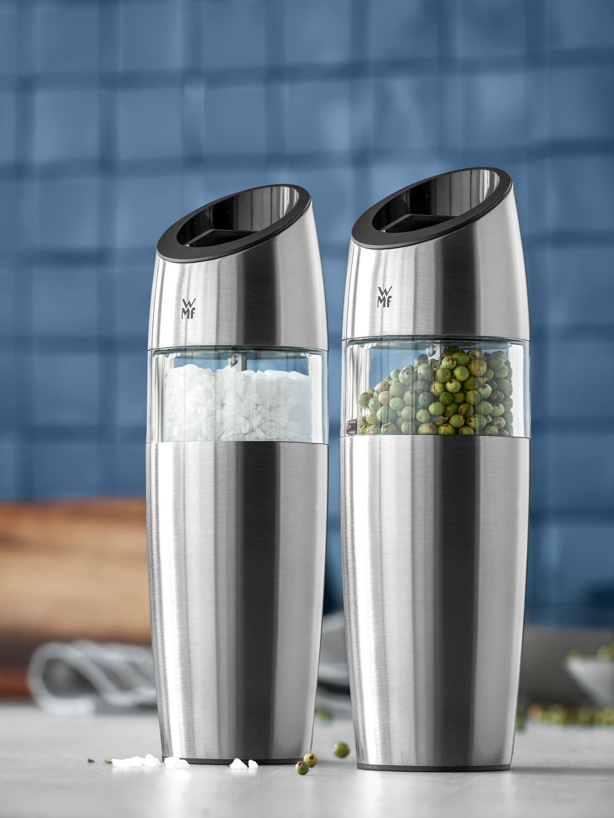 Zweier-Set aus elektrischen Mühlen aus Edelstahl, gefüllt mit Salz und Pfeffer, in einer modernen Küche, seitliche Perspektive