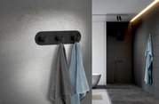 Dreierhaken aus schwarzem Edelstahl an einer Badezimmerwand, frontal betrachtet, mit zwei aufgehängten Handtüchern in Grau und Blau.