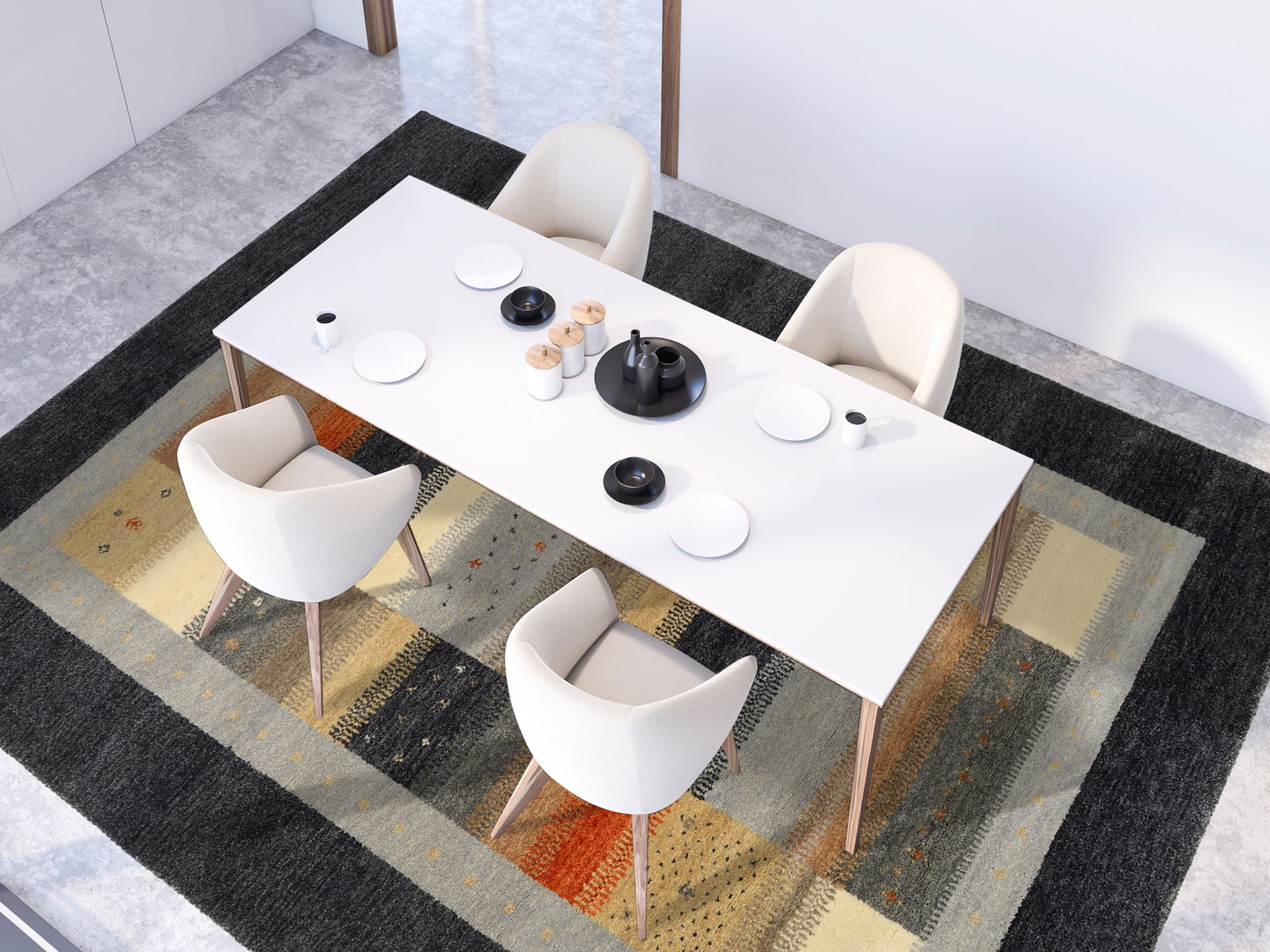 Moderner Essbereich mit einem großen, rechteckigen Tisch und vier weißen Stühlen auf einem bunten Wollteppich mit geometrischen Mustern, aus der Vogelperspektive betrachtet.