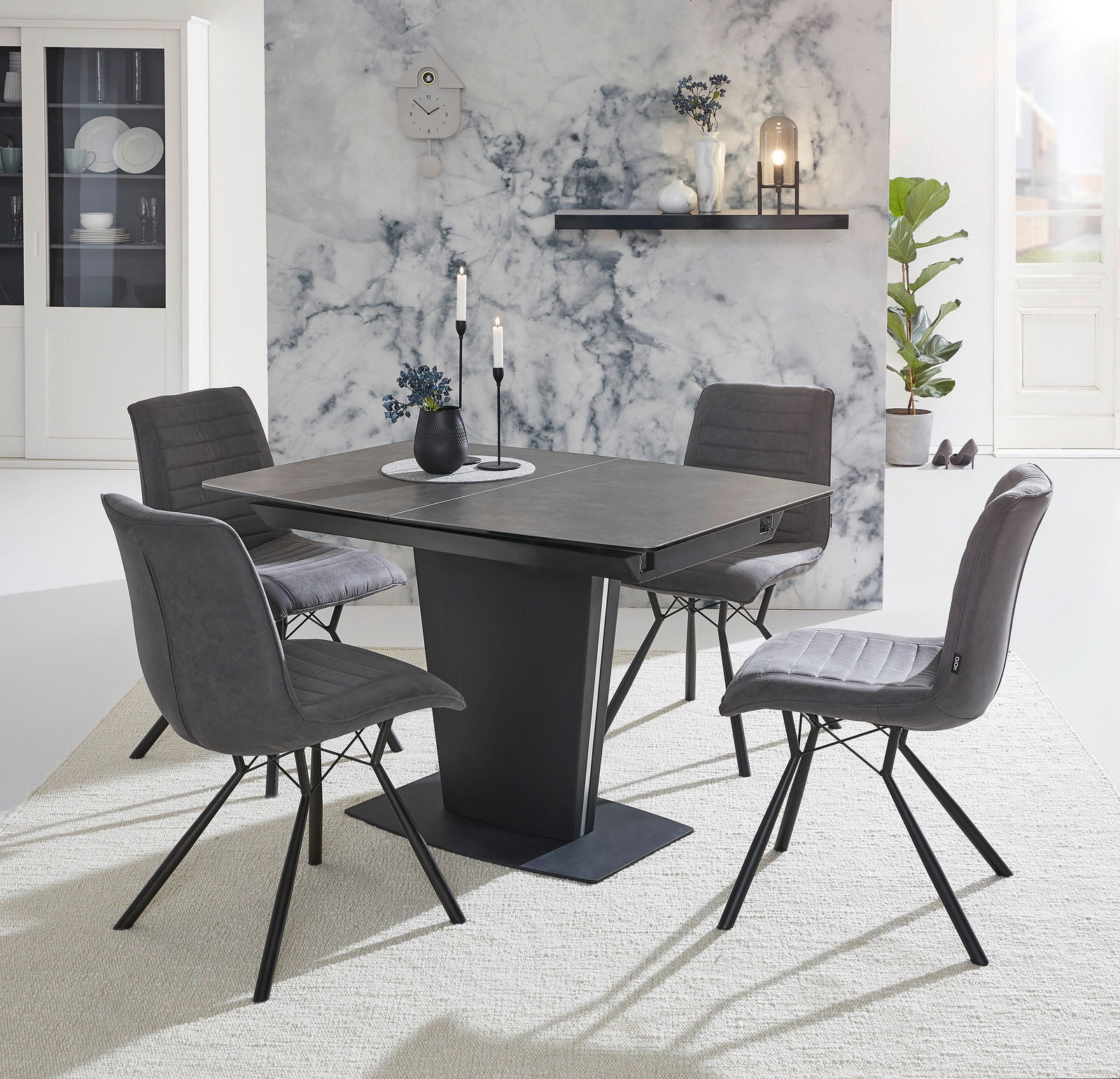 Moderner Esstisch mit vier grauen Stühlen, frontal fotografiert, vor einer stilvollen Marmorwand.