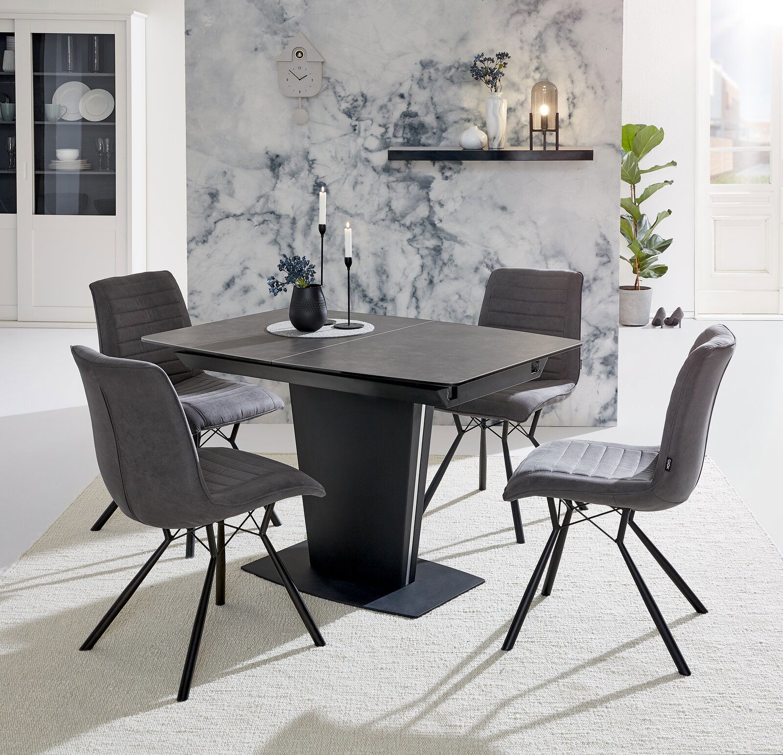 Moderner Esstisch mit vier grauen Stühlen, frontal fotografiert, vor einer stilvollen Marmorwand.