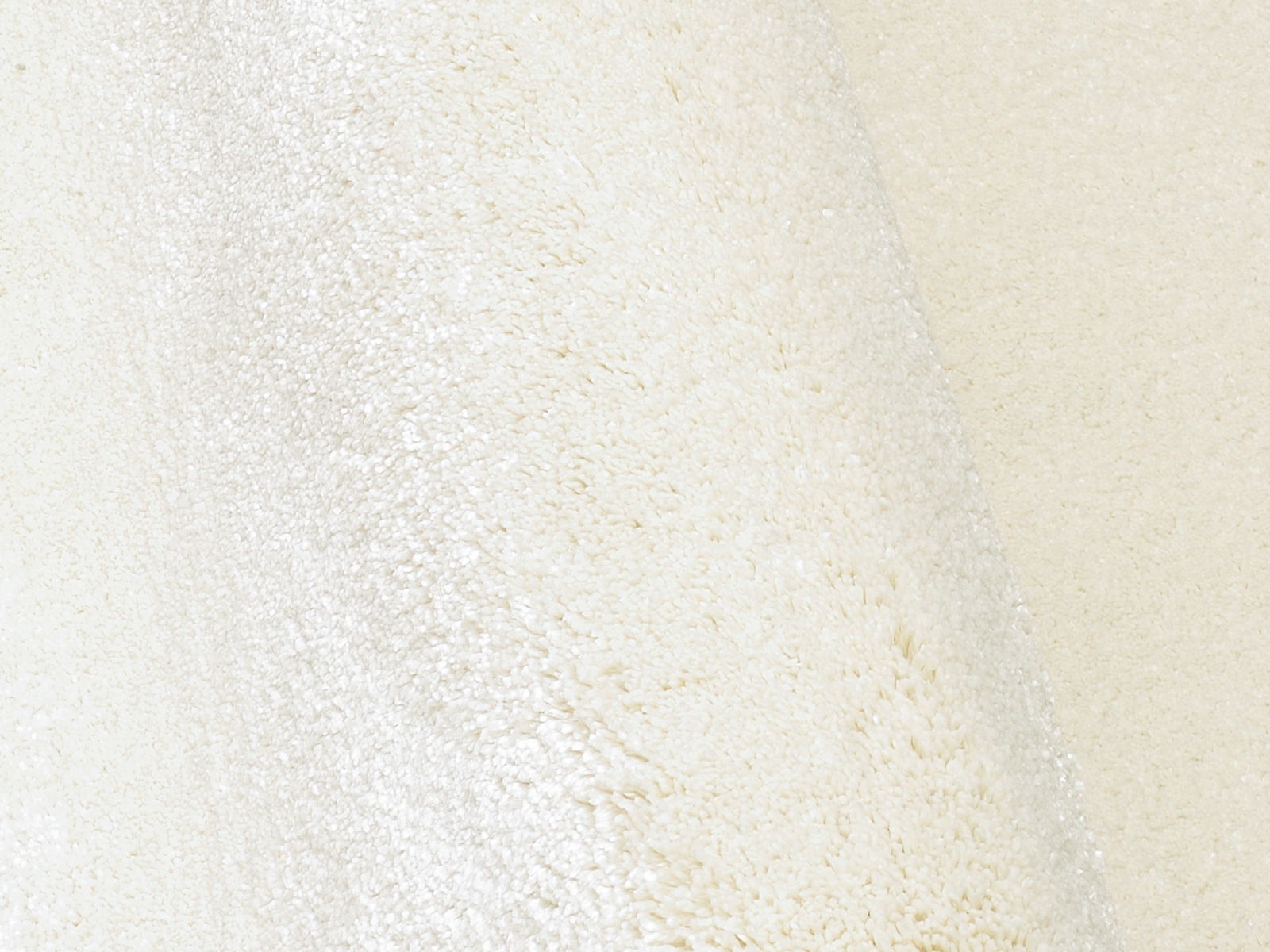 Nahaufnahme eines cremeweißen Uni-Teppichs mit weicher Textur, seitliche Perspektive