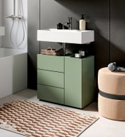 Modernes Badezimmer mit grünem Waschtischunterschrank und weißem Aufsatzwaschbecken, Armatur und Accessoires vor dunkler Wand; Perspektive: frontale Ansicht leicht von rechts.