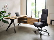 Moderner Eck-Schreibtisch aus Holz mit schwarzem Metallgestell, seitliche Perspektive, ausgestattet mit Laptop und Schreibtischlampe, neben einem ergonomischen Bürostuhl.