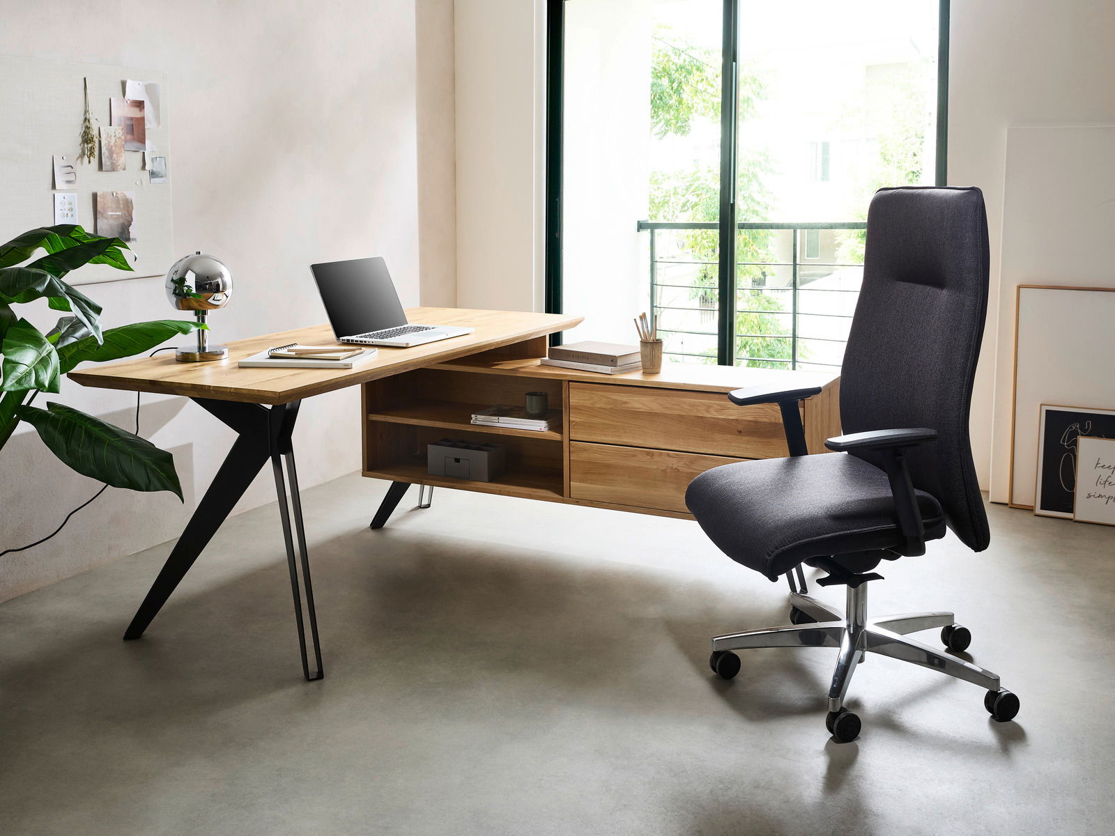 Moderner Eck-Schreibtisch aus Holz mit schwarzem Metallgestell, seitliche Perspektive, ausgestattet mit Laptop und Schreibtischlampe, neben einem ergonomischen Bürostuhl.