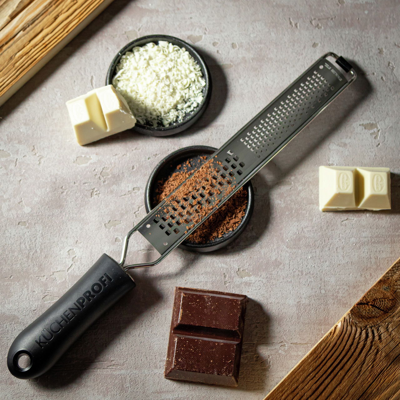 Feine und grobe Reibe von KÜCHENPROFI, von oben fotografiert, umgeben von geriebener Schokolade und Schokoladenstücken.