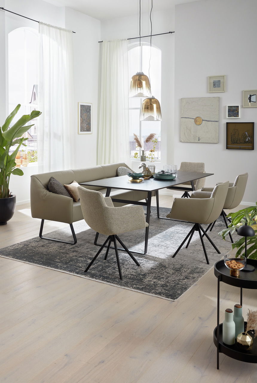 Esszimmer mit moderner Sitzgruppe, bestehend aus einem Tisch, einer Eckbank und mehreren Sesseln, aus seitlicher Perspektive fotografiert.