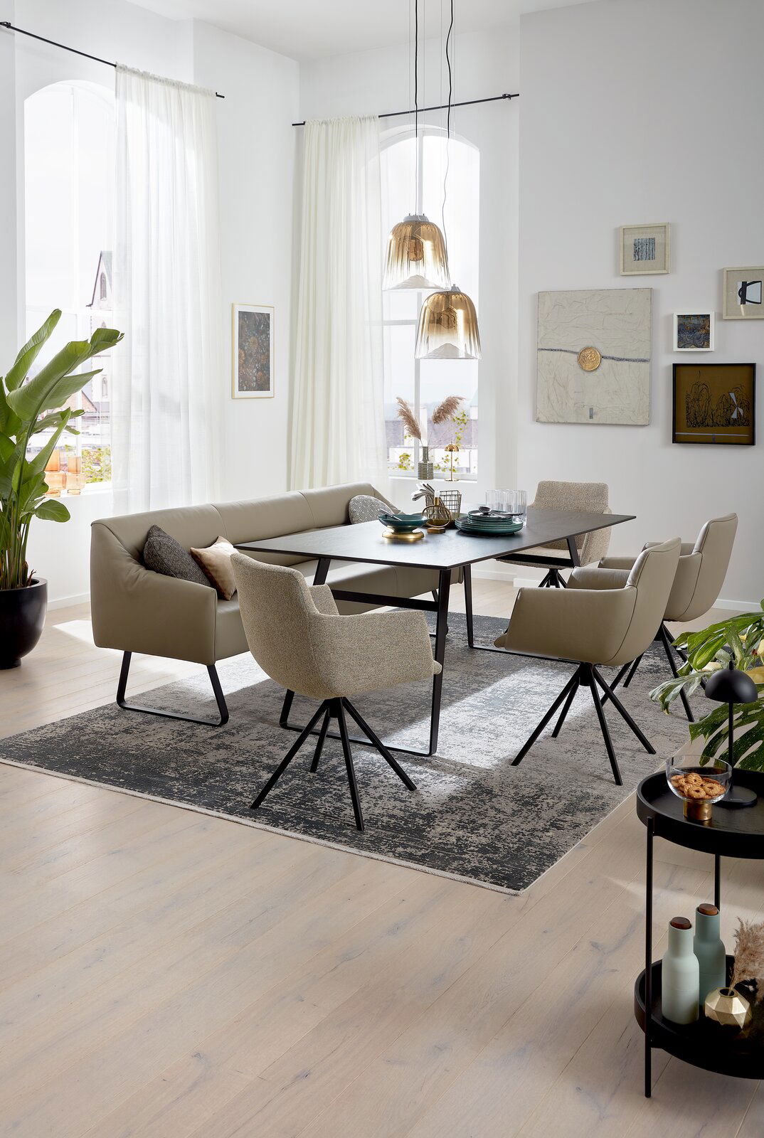 Esszimmer mit moderner Sitzgruppe, bestehend aus einem Tisch, einer Eckbank und mehreren Sesseln, aus seitlicher Perspektive fotografiert.