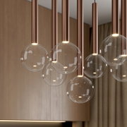 Moderne Pendelleuchte mit mehreren transparenten Glaskugeln und kupferfarbenen Zylindern, warmes Licht, Innenraumaufnahme aus leicht schräger Untersicht