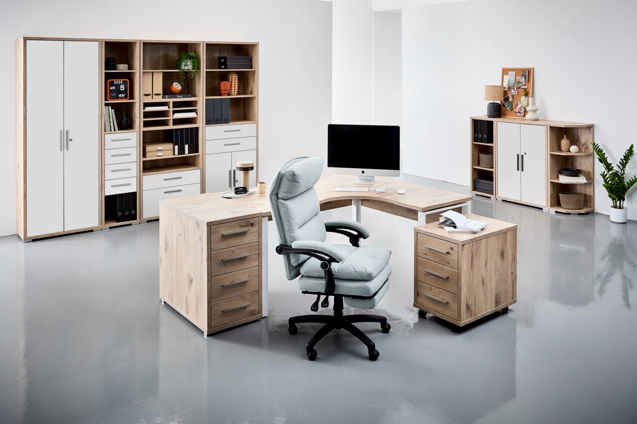 Moderne Büroumgebung mit Eckschreibtisch, Rollcontainer und Regalen in Holzoptik, aus der Perspektive eines Betrachters im Raum.