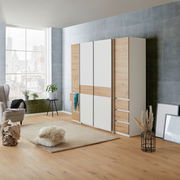 Moderner Dreh- und Schwebetürenschrank mit vier Türen in Holz- und Weißoptik, seitliche Perspektive im stilvollen Wohnzimmer.