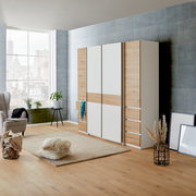 Moderner Dreh- und Schwebetürenschrank mit vier Türen in Holz- und Weißoptik, seitliche Perspektive im stilvollen Wohnzimmer.