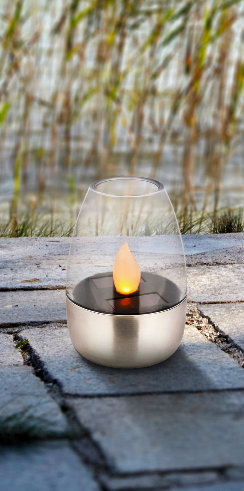 Solarbetriebene Gartenleuchte mit flammenförmigem Licht, auf Steinboden im Freien platziert, seitliche Perspektive.