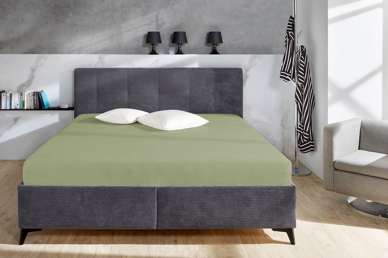 Novel Spannbetttuch TEDDY-FLAUSCH Grünes Spannbetttuch auf einem grauen Bett in einem modernen Schlafzimmer, frontal aufgenommen.