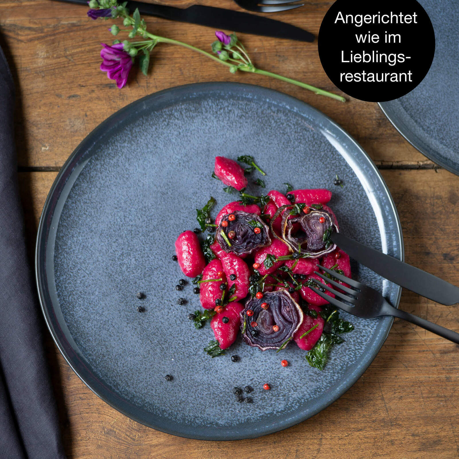 Blauer Teller mit elegant angerichtetem Essen, fotografiert aus der Vogelperspektive.