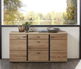 Holz-Sideboard mit mehreren Schubladen und Türen, dekoriert mit Vasen und Schalen, vor einem großen Fenster mit Blick auf einen See. Frontalansicht.