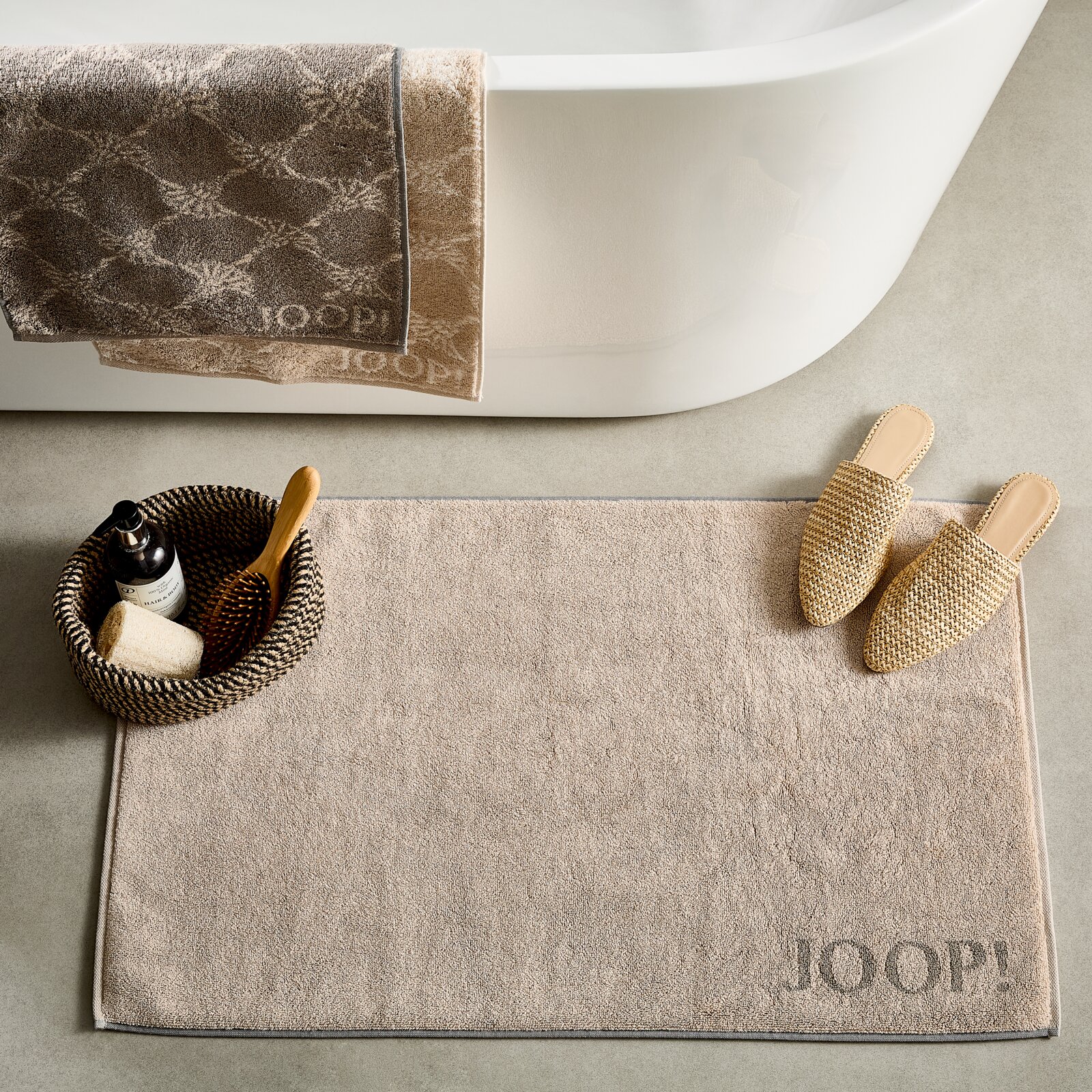 JOOP! Badematte DOUBLEFACE Badematte in Beige vor einer Badewanne, mit einem Korb und Hausschuhen daneben, von oben betrachtet.