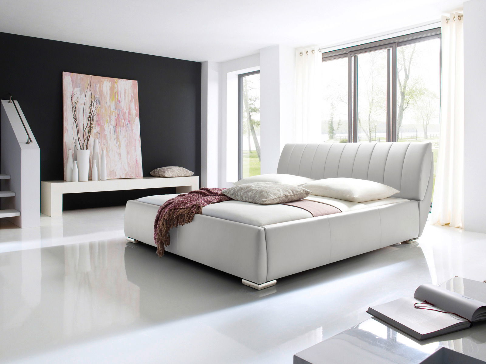 Modernes Polsterbett in einem hellen Raum mit großen Fenstern, seitliche Perspektive