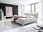 Modernes Polsterbett in einem hellen Raum mit großen Fenstern, seitliche Perspektive