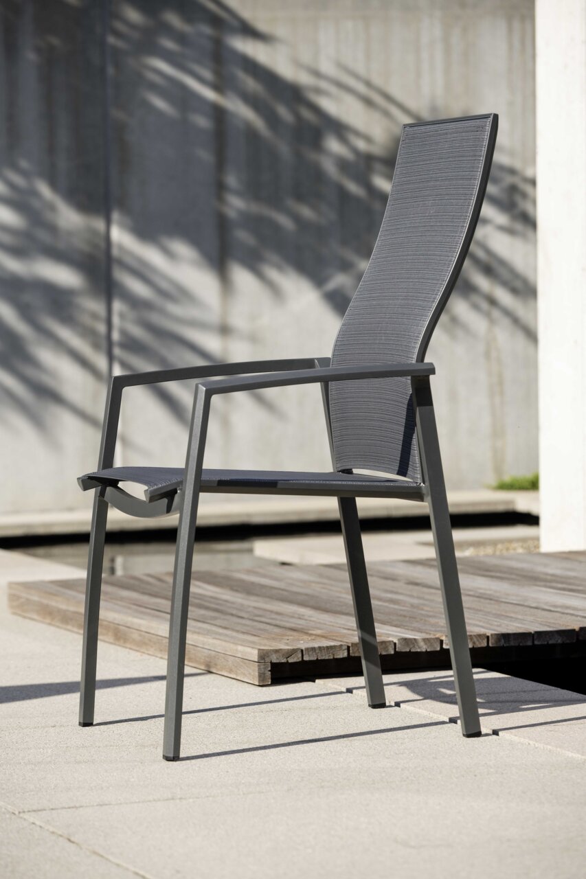Moderner Stapelsessel KARI aus Metall mit hoher Rückenlehne, seitliche Perspektive, auf einer Terrasse platziert.