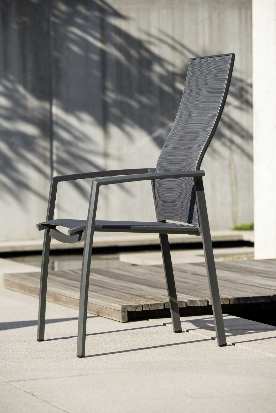 Moderner Stapelsessel KARI aus Metall mit hoher Rückenlehne, seitliche Perspektive, auf einer Terrasse platziert.