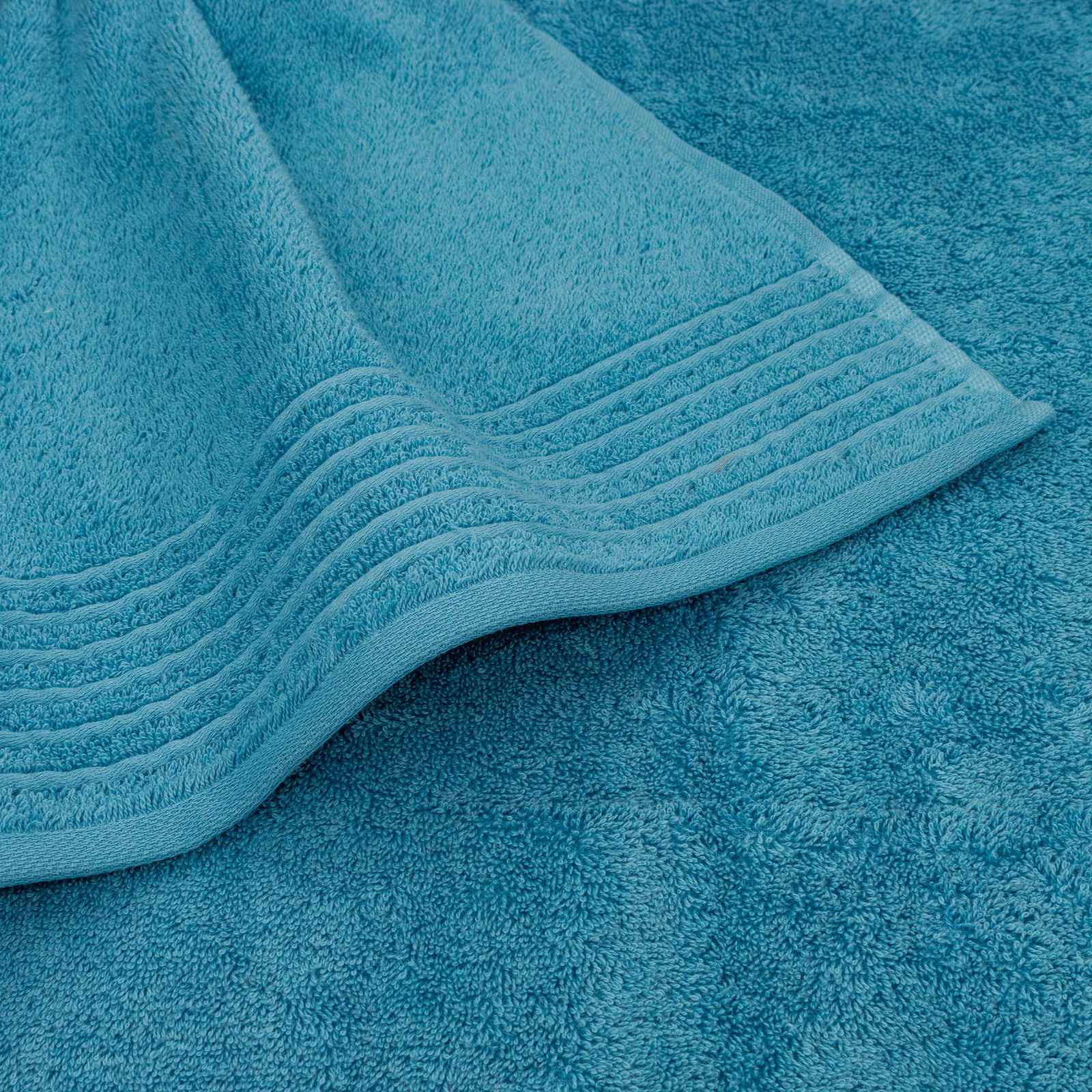 Nahaufnahme eines türkisfarbenen Handtuchs mit dekorativen Streifen am Rand.