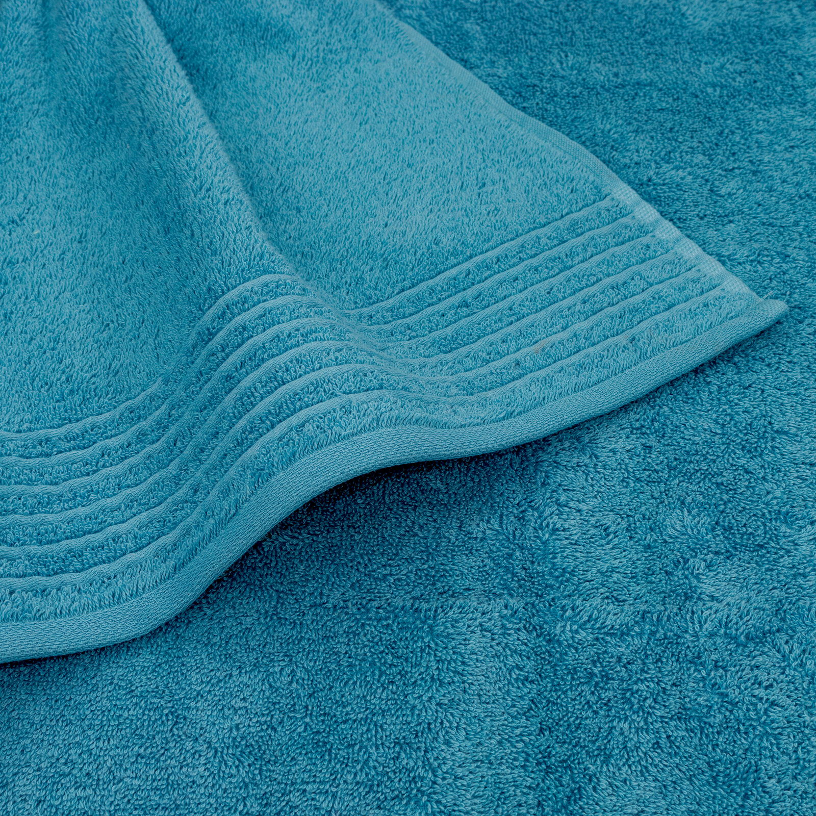 Nahaufnahme eines türkisfarbenen Handtuchs mit dekorativen Streifen am Rand.