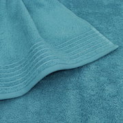 Close-up van een turquoise handdoek met decoratieve strepen aan de rand.