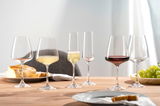 Sechs elegante Weingläser auf einem Tisch, gefüllt mit Rot- und Weißwein, aus seitlicher Perspektive fotografiert.