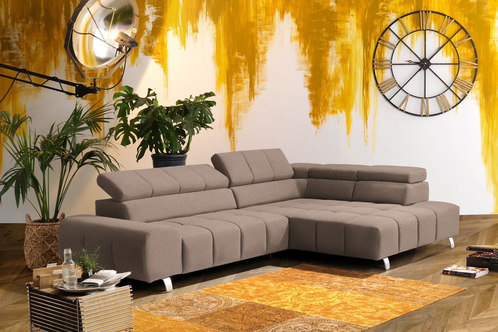 Moderne braune Rundecke mit Ottomane rechts, in einem stilvoll eingerichteten Wohnzimmer mit gelber Akzentwand, Pflanzen und großer Wanduhr. Perspektive von vorne links.