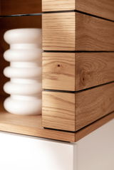 Nahaufnahme eines modernen Sideboards aus Holz mit klaren Linien und einem weißen Element, perspektivisch von der Seite aufgenommen.