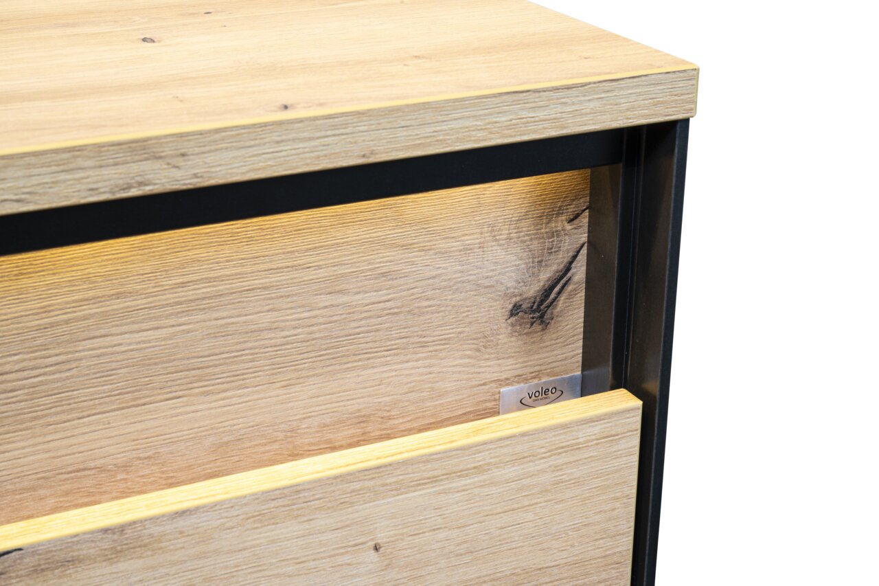 Detailfoto van een nachtkastje van licht hout met een zwart frame, gezien vanaf de zijkant