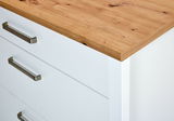 Nahaufnahme eines weißen Schubkastenunterschranks mit Holzoberfläche und Metallgriffen, Perspektive von oben.