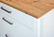 Nahaufnahme eines weißen Schubkastenunterschranks mit Holzoberfläche und Metallgriffen, Perspektive von oben.