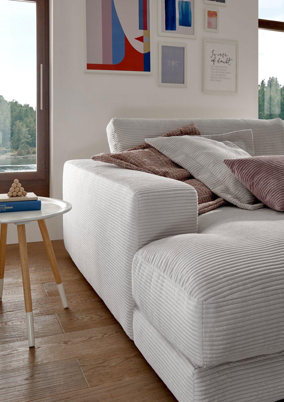 Großes, gemütliches Megasofa in einem modernen Wohnzimmer, seitliche Perspektive mit mehreren Kissen und einem Beistelltisch.